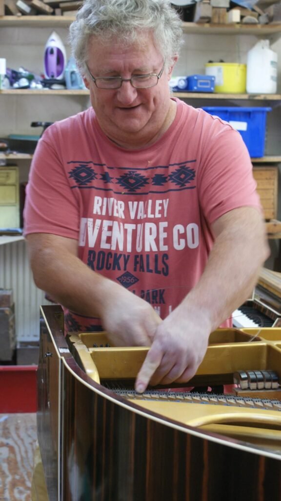 Piano technician tuning grand piano after relocation