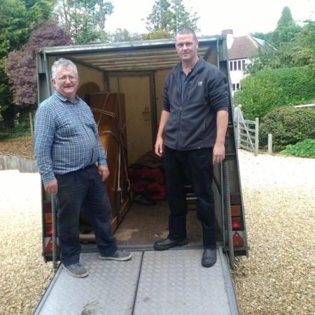 Smiling piano movers team standing beside their van Sussex