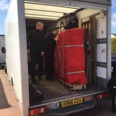 Professional piano moving team securing piano in transport van